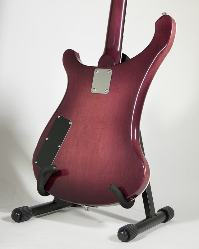 A purple guitar is sitting on a black stand