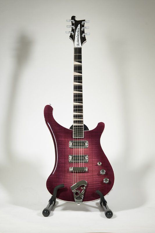 A purple electric guitar is sitting on a stand.