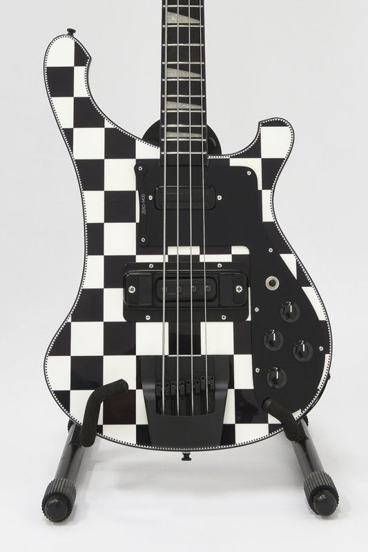 A black and white checkered bass guitar on a stand