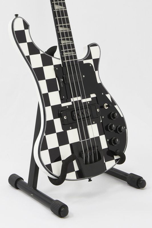 A black and white checkered electric guitar on a stand