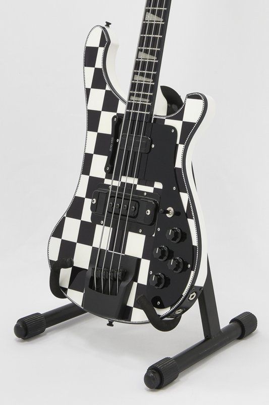 A black and white checkered electric guitar on a stand
