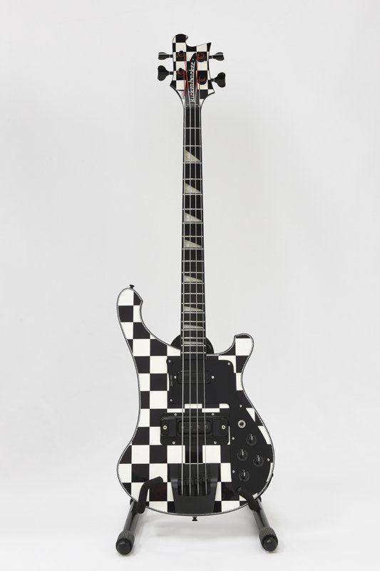 A black and white checkered bass guitar on a stand