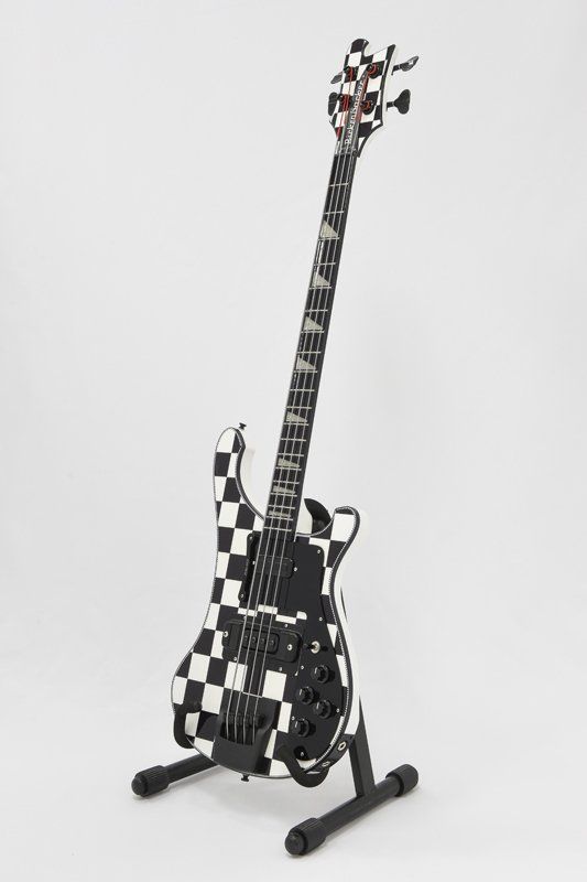 A black and white checkered bass guitar on a stand