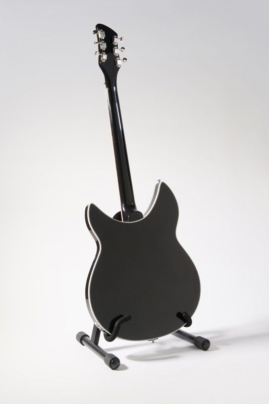A black guitar is sitting on a stand on a white background