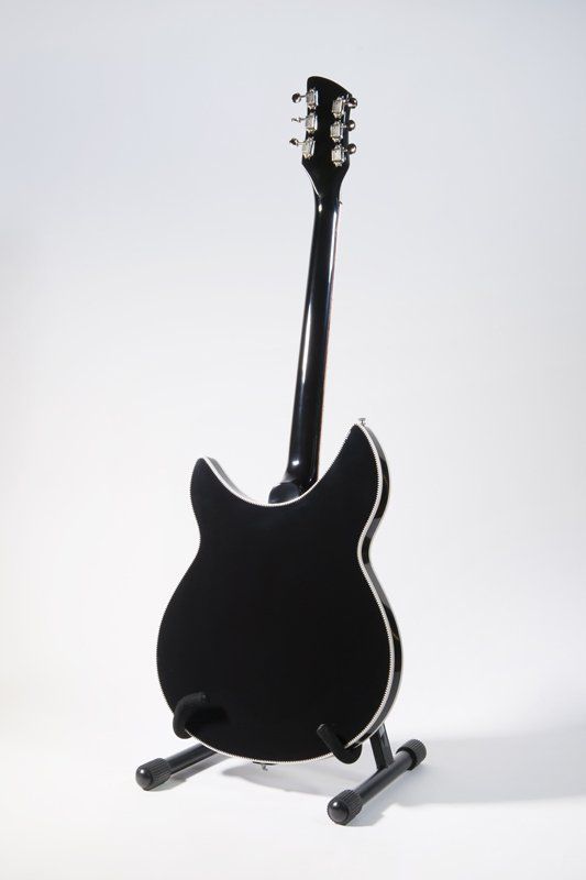 A black guitar is sitting on a stand on a white background