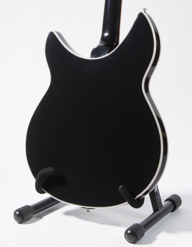 A black guitar is sitting on a stand on a white background