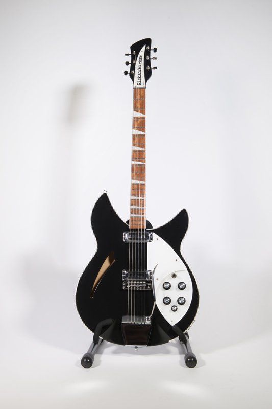 A black and white electric guitar is sitting on a stand.