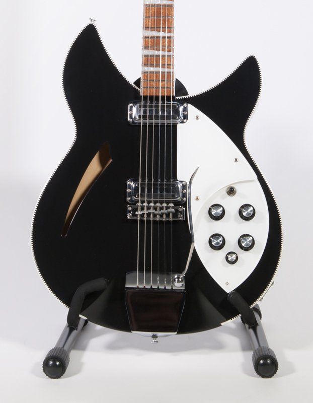 A black and white guitar is sitting on a stand