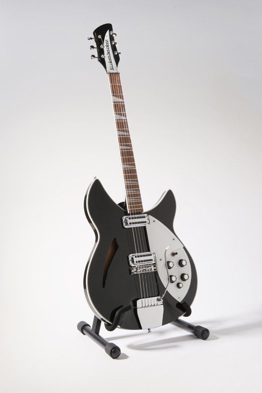 A black and white guitar is sitting on a stand