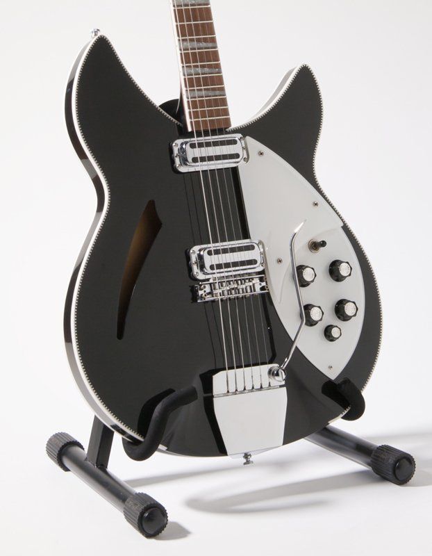 A black and white guitar is sitting on a stand