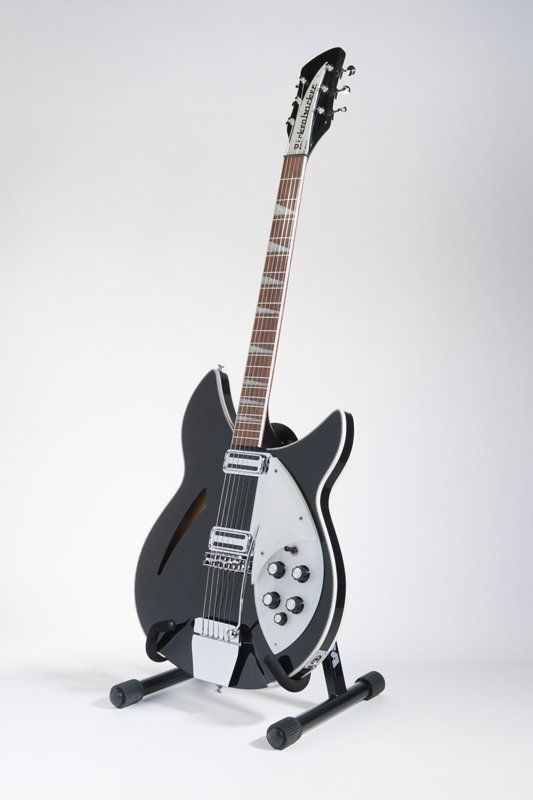 A black and white guitar is sitting on a stand