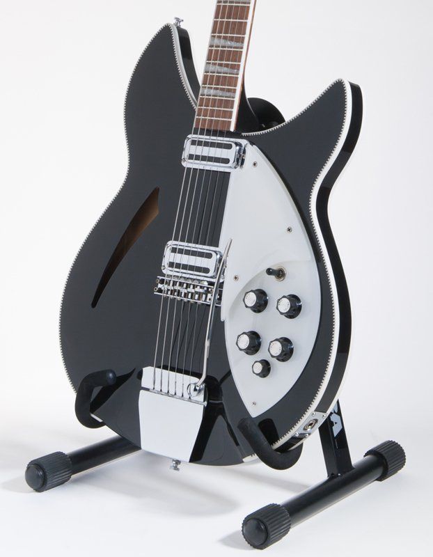 A black and white guitar is sitting on a stand