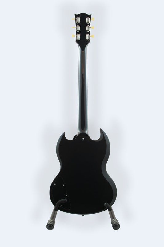 A black electric guitar is sitting on a stand on a white background.