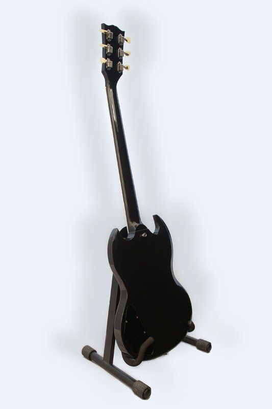 A black electric guitar is sitting on a stand.