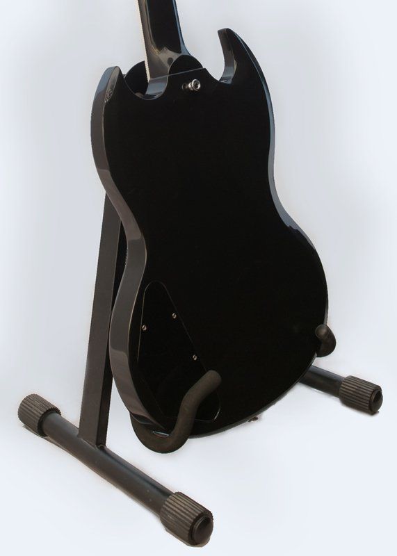 A black guitar is sitting on a black stand