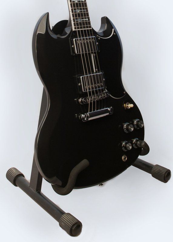 A black electric guitar is sitting on a stand