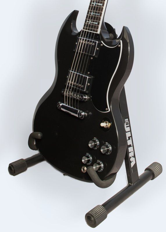A black guitar is sitting on a delta stand