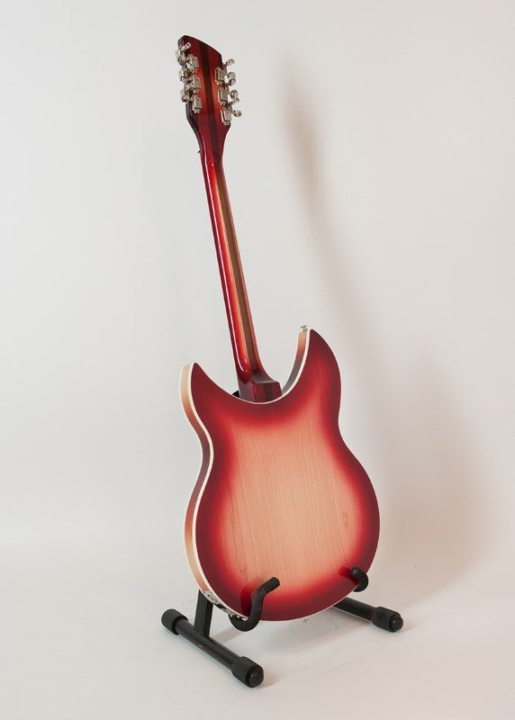 A red electric guitar is sitting on a stand