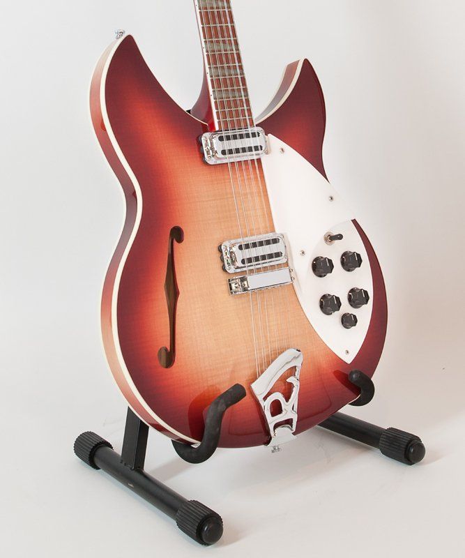 A red guitar is sitting on a black stand