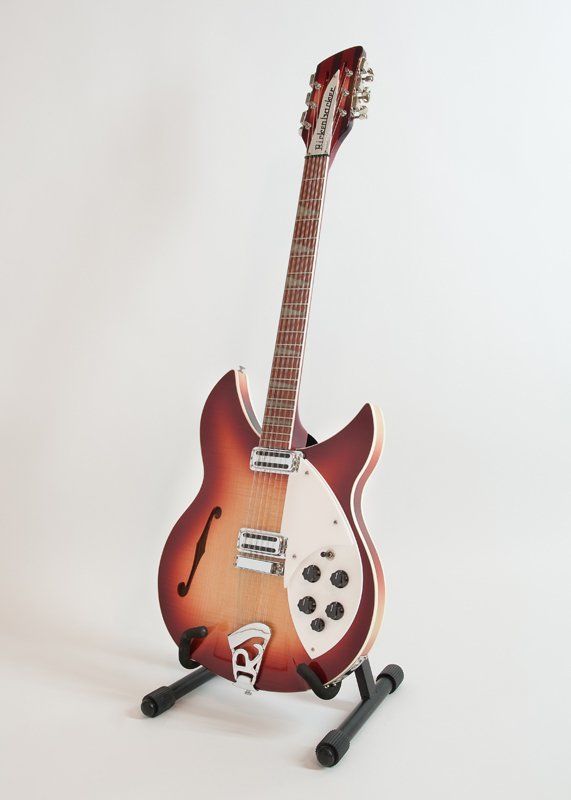 A guitar is sitting on a stand on a white background.