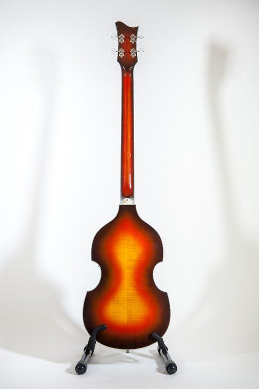A double bass guitar is sitting on a stand on a white background.