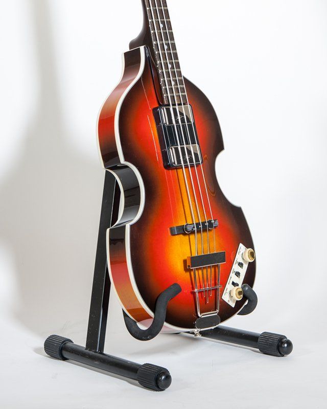 A bass guitar is sitting on a stand on a white background