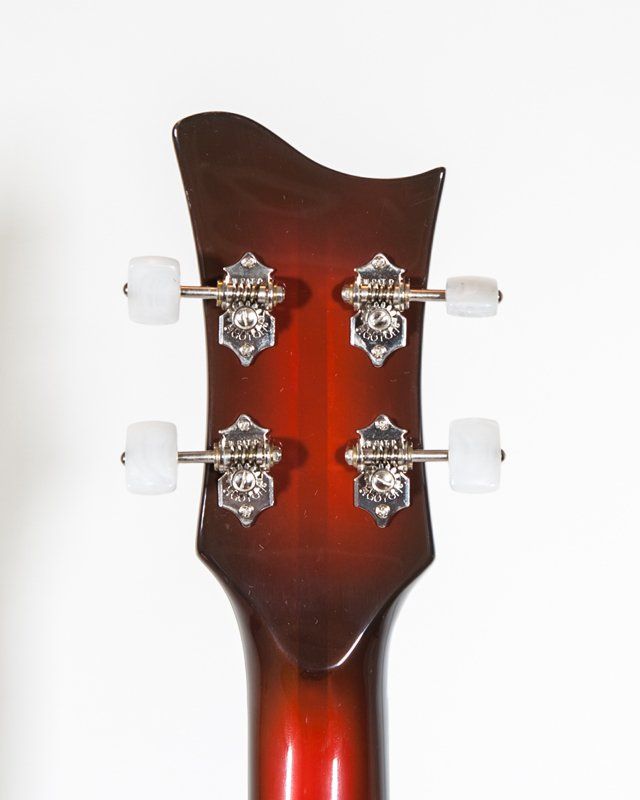 A close up of a guitar headstock with white knobs