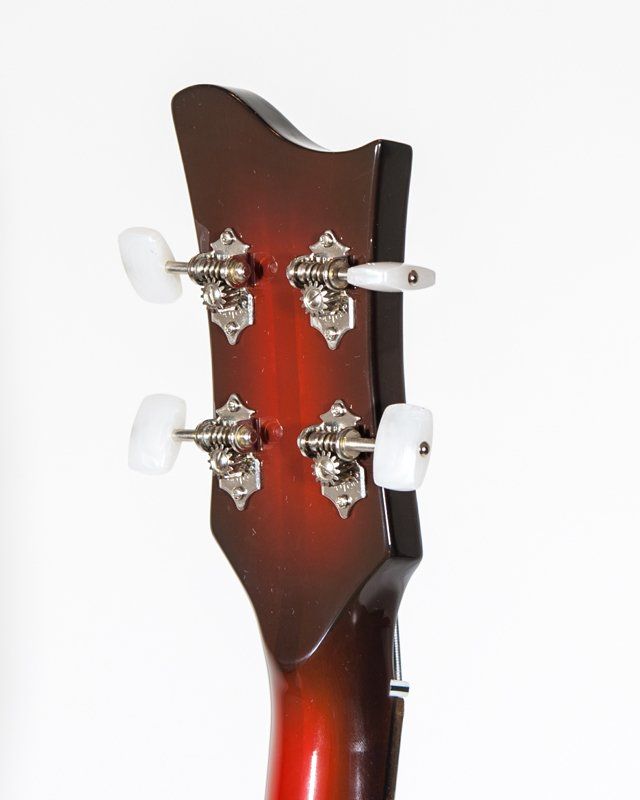 A close up of a guitar headstock with white knobs