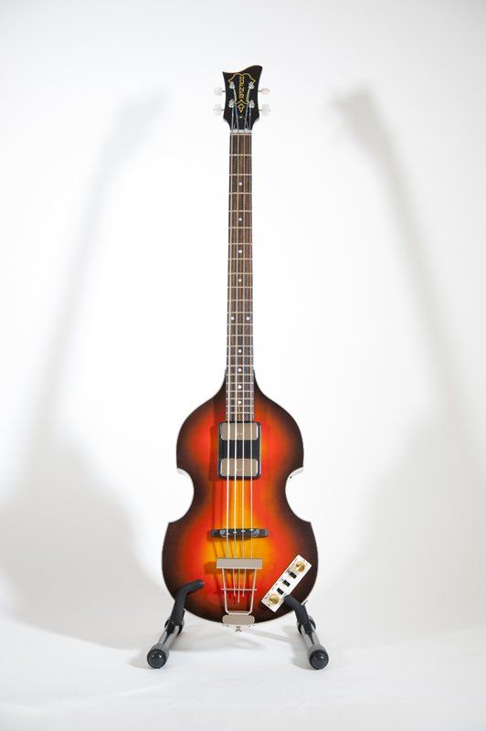A bass guitar is sitting on a stand on a white background
