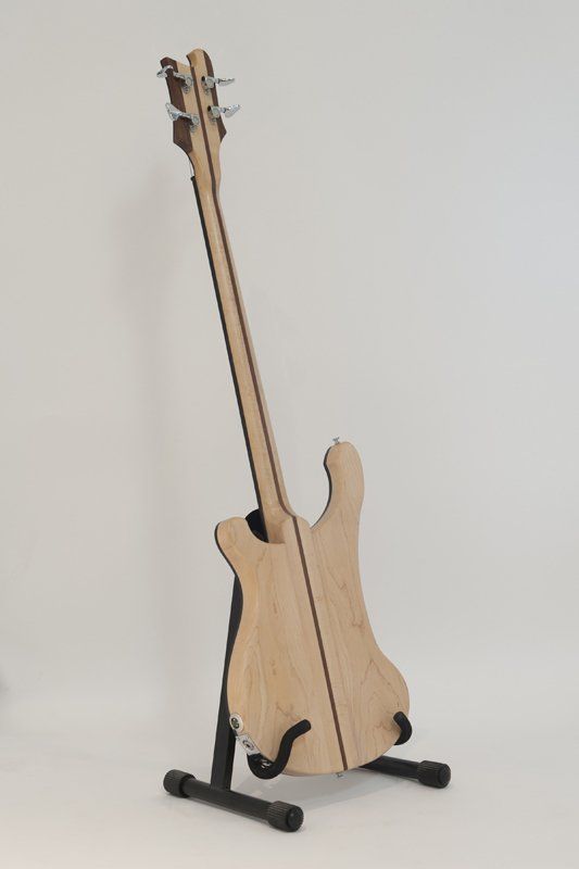A bass guitar is sitting on a stand against a white background