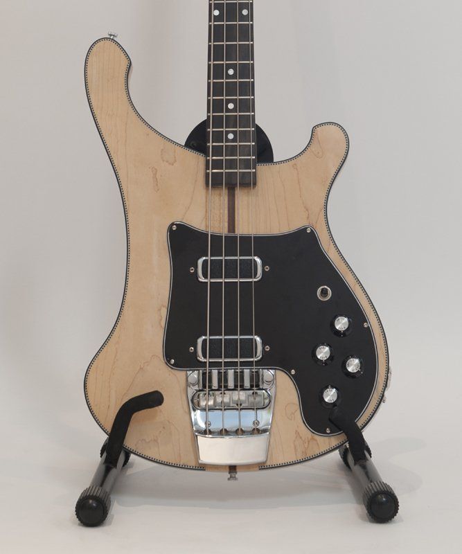 A bass guitar is sitting on a stand against a white background
