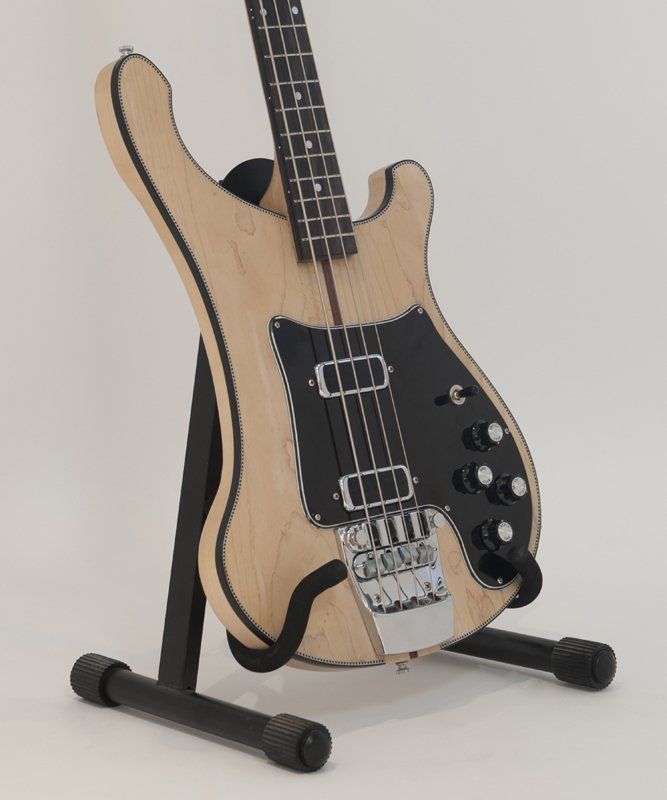 A bass guitar is sitting on a black stand