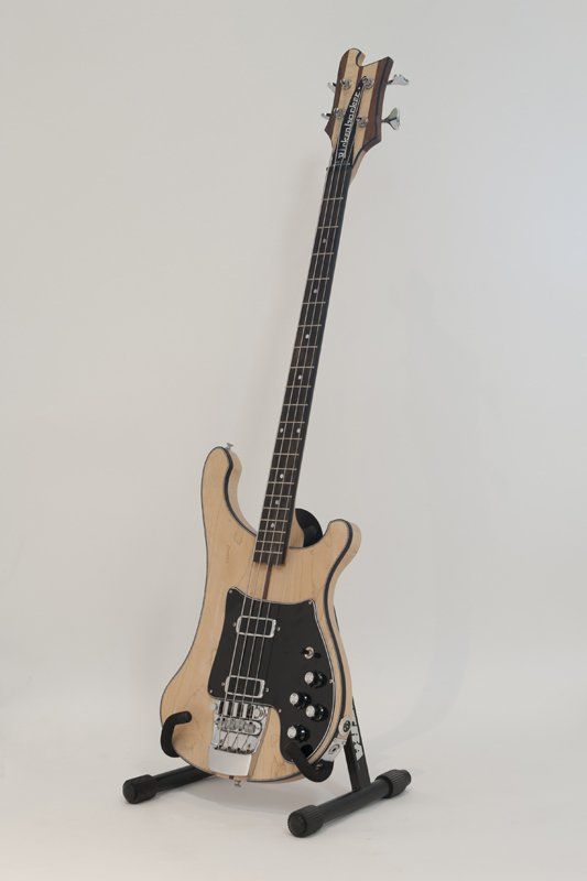 A bass guitar is sitting on a stand on a white surface.