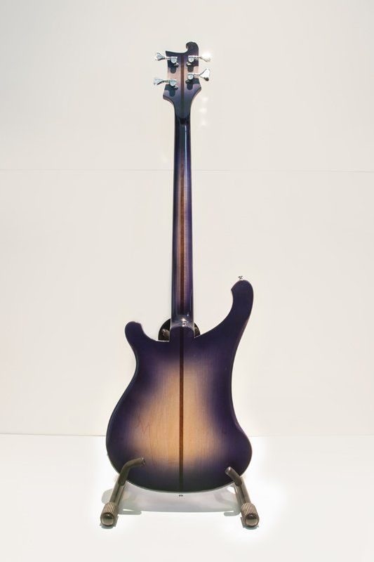 A purple and gold electric guitar is sitting on a stand.
