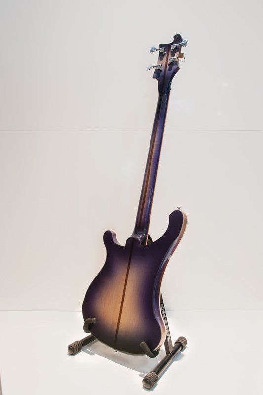 A purple electric guitar is sitting on a stand.