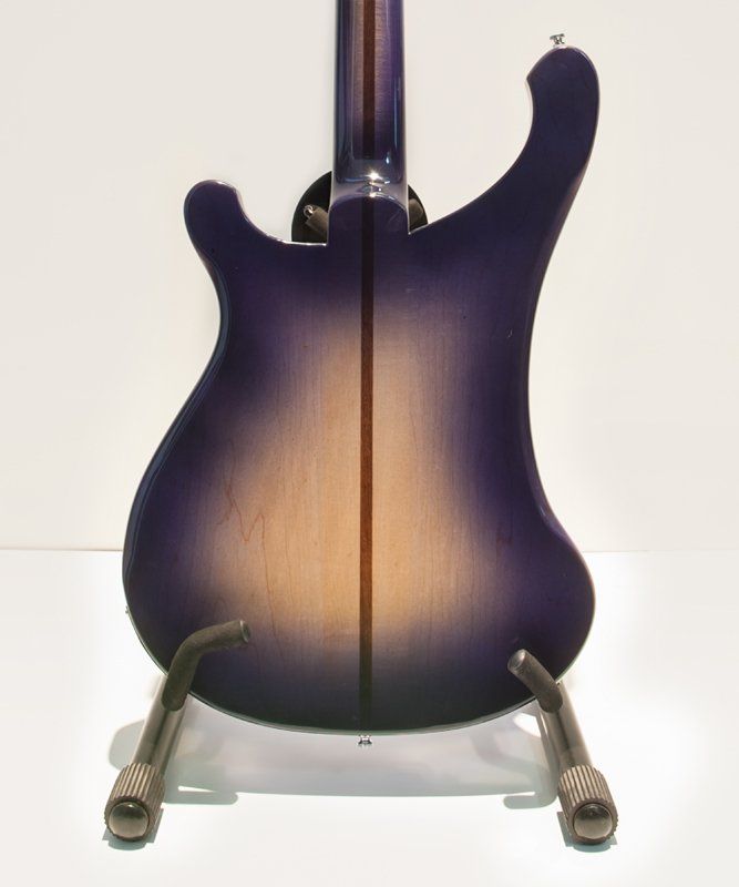 A purple electric guitar is sitting on a stand