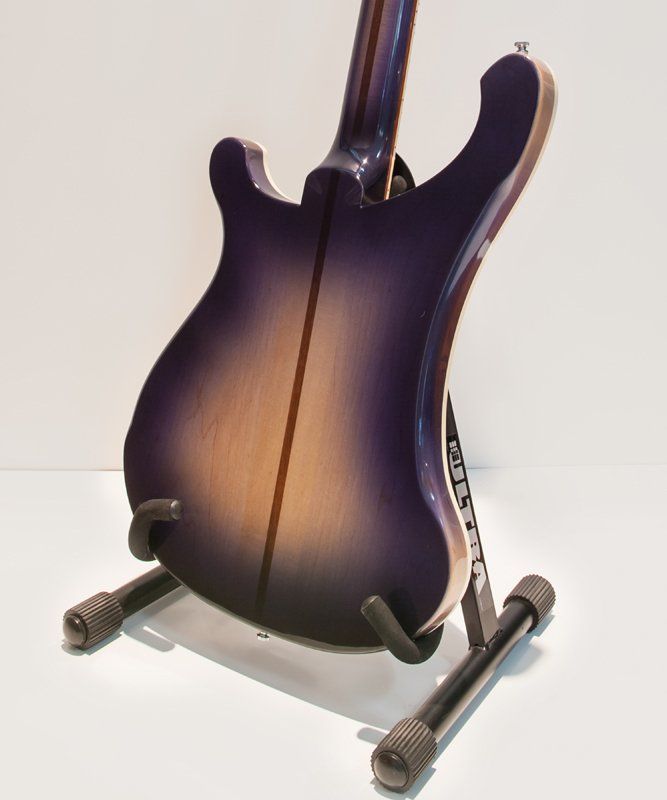 A purple electric guitar is sitting on a stand
