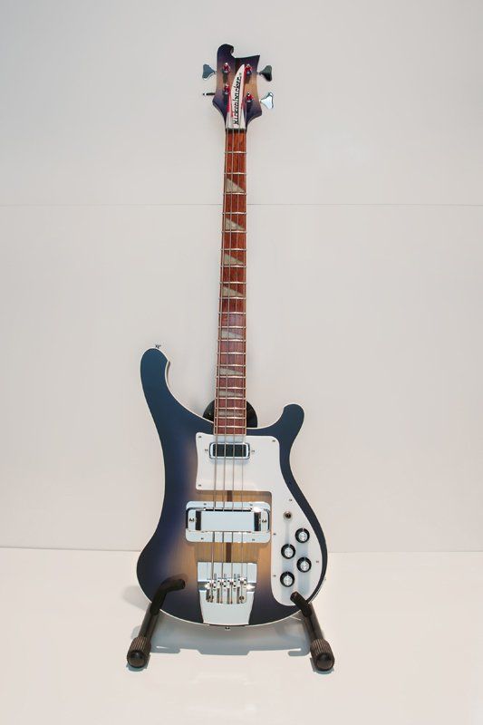 A blue and white electric guitar is sitting on a stand.