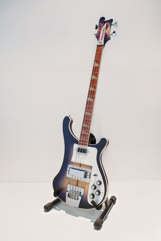 A guitar is sitting on a stand on a table.