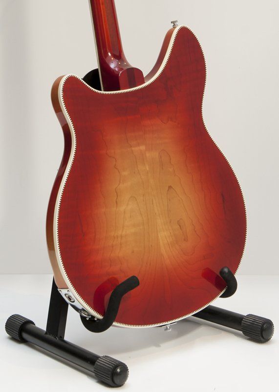 A red guitar is sitting on a black stand