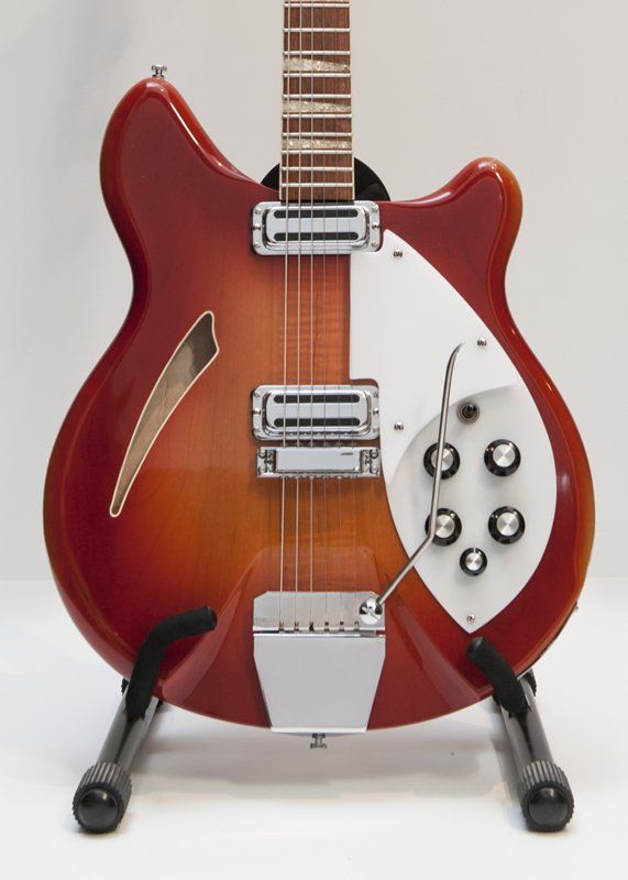 A red and white guitar is sitting on a stand