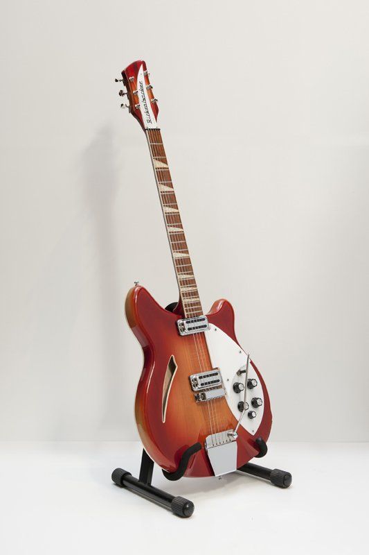 A red and white electric guitar is sitting on a stand.
