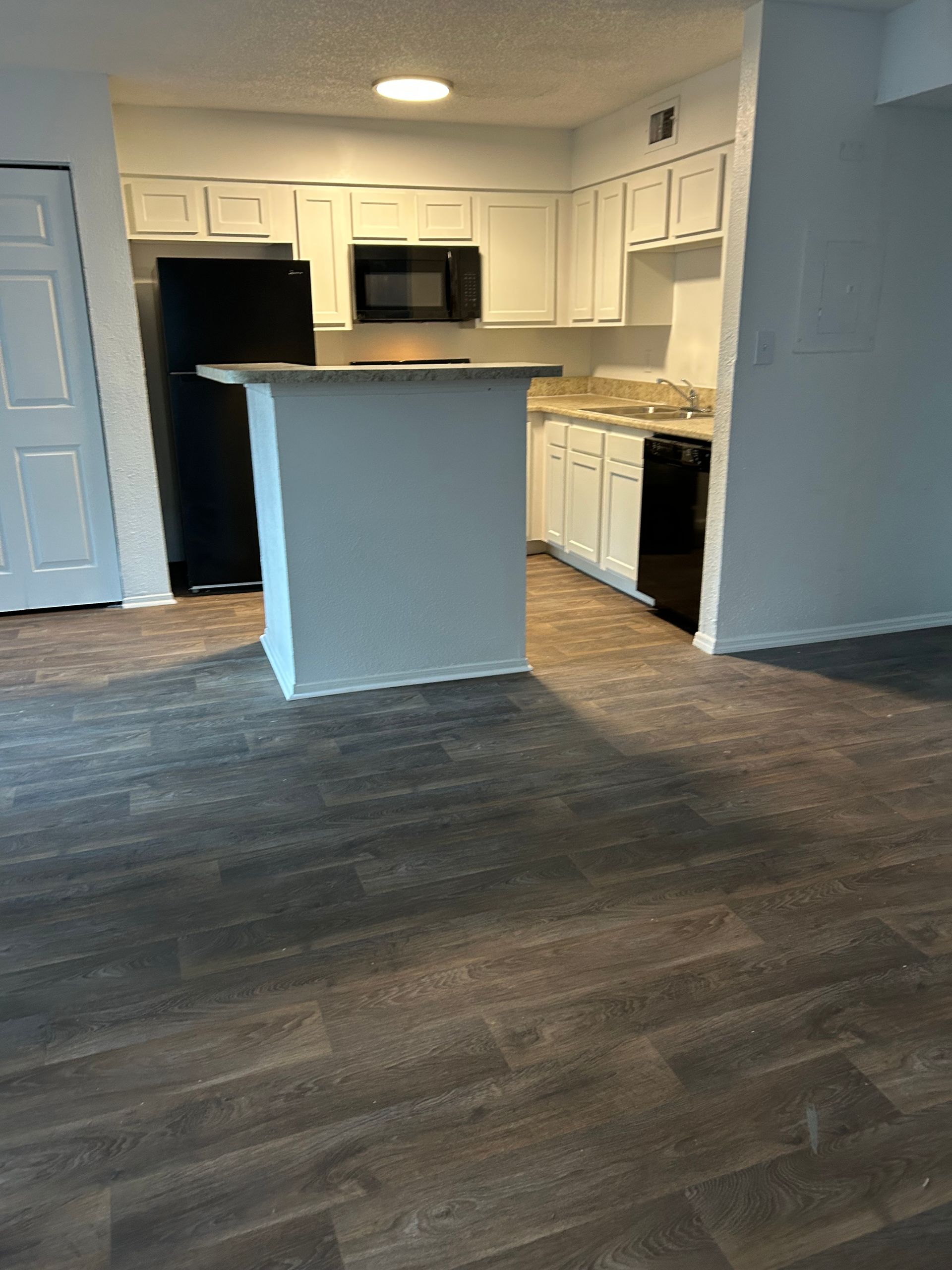 Kitchen with white cabinets, black appliances, granite countertops, and wood-look flooring.