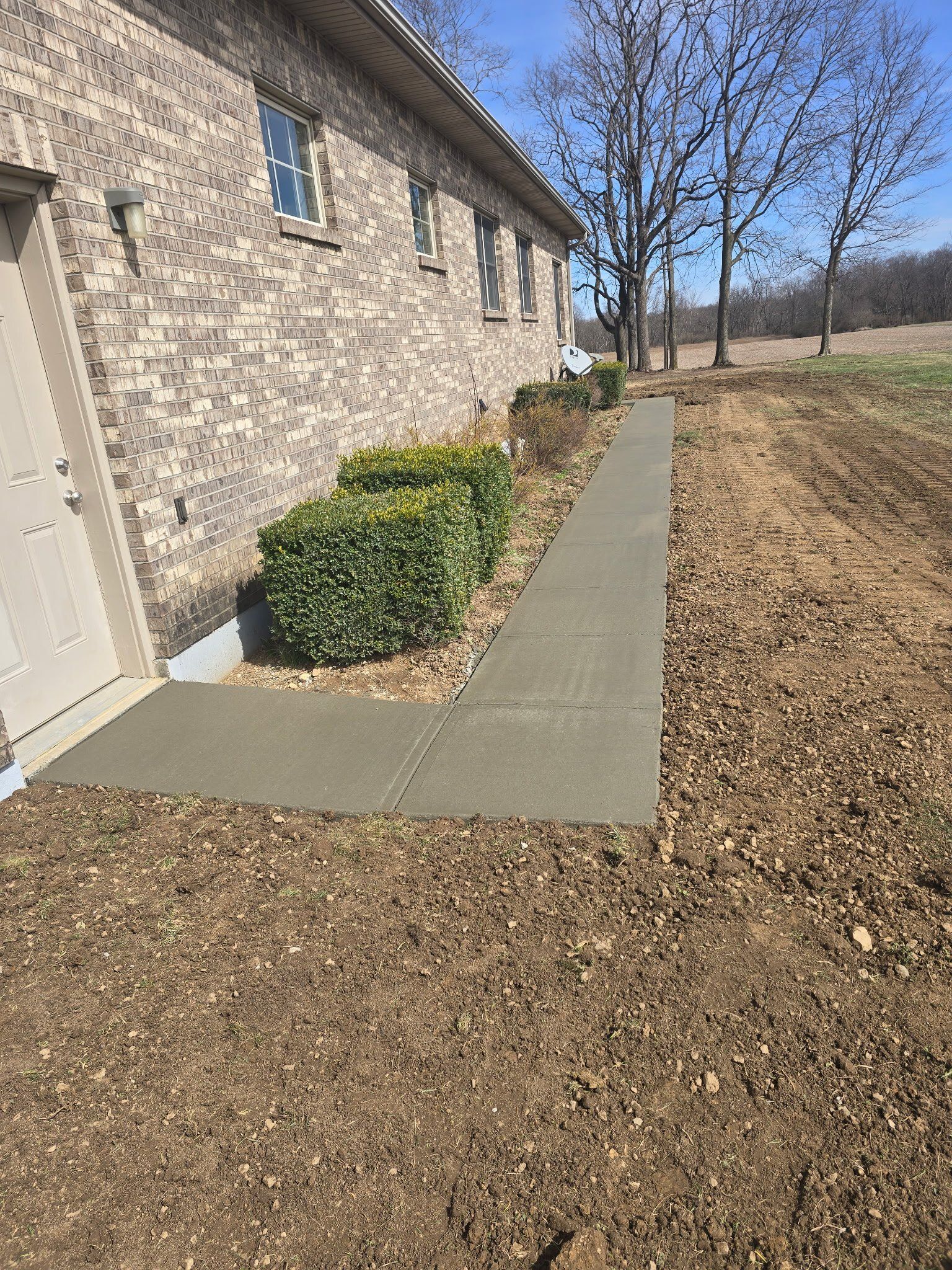 A concrete walkway is being built in front of a brick house.