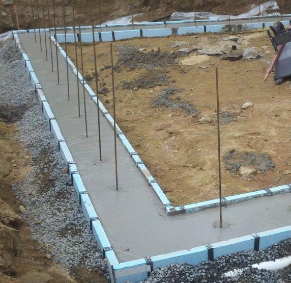 A concrete foundation is being built in a dirt field