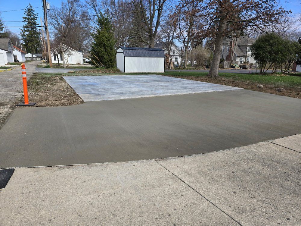 A concrete driveway with a shed in the background
