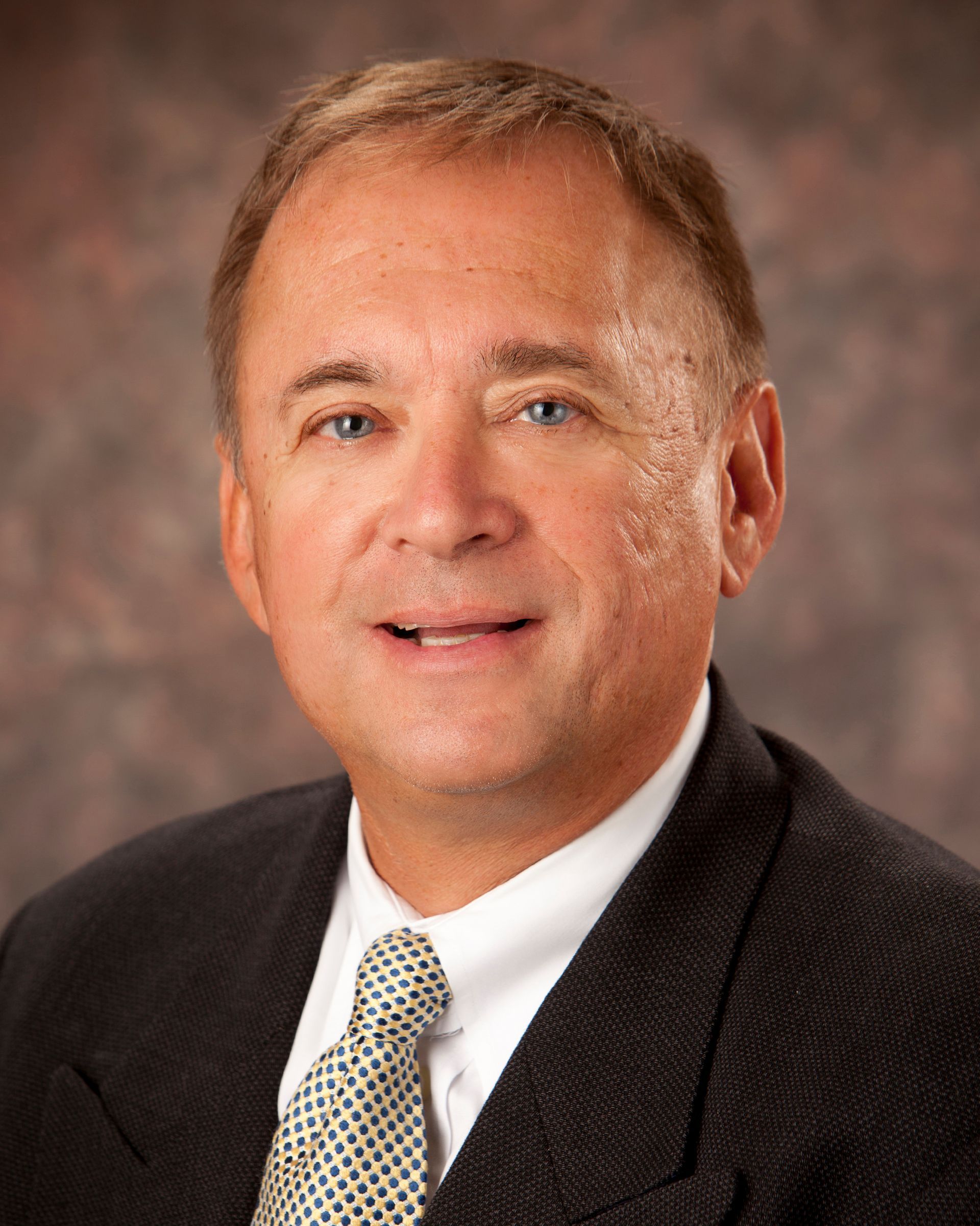 A man in a suit and tie is smiling for the camera