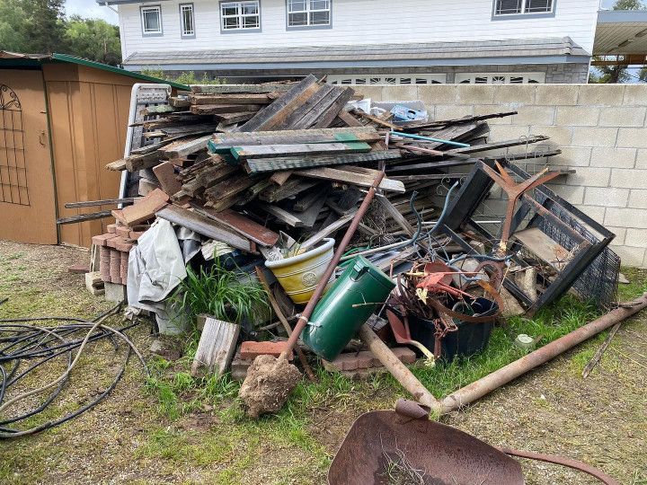 A pile of wood is sitting in the grass in front of a house.