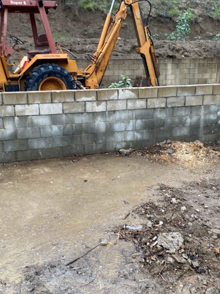 A tractor is digging a hole in a brick wall.