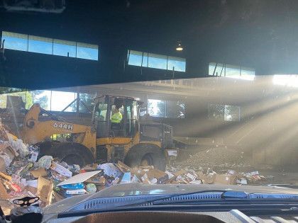 A man is driving a bulldozer in a dumpster.